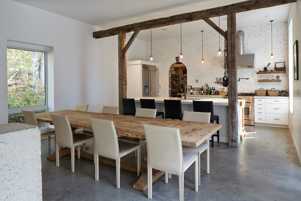 Country u-shaped concrete floor kitchen/dining room combo photo in New York with flat-panel cabinets, white cabinets and stainless steel appliances