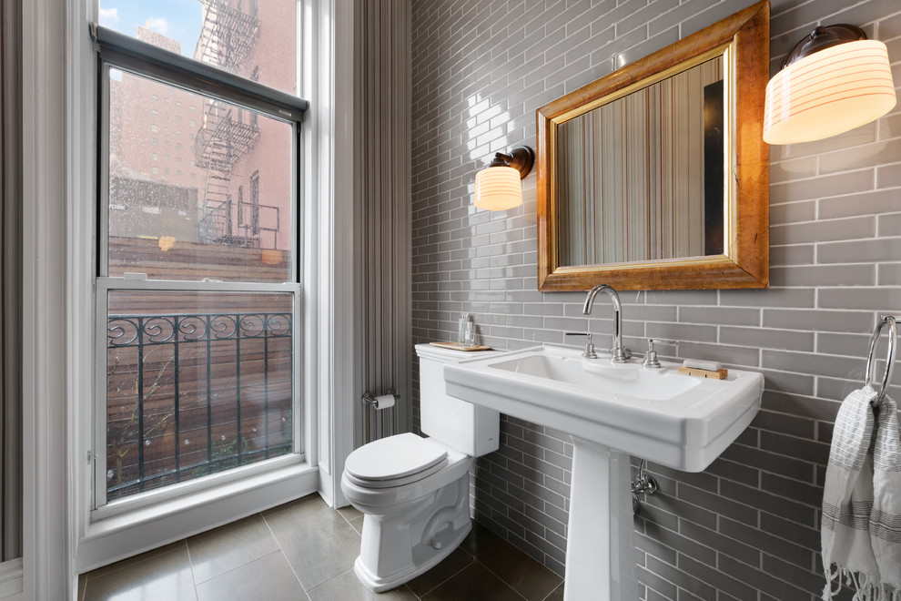 Design ideas for a small transitional powder room in New York with a two-piece toilet, gray tile, a pedestal sink, grey floor, limestone floors and ceramic tile.
