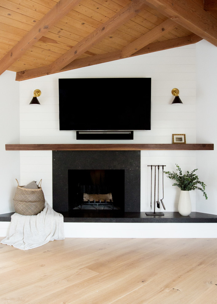 Inspiration for a mid-sized transitional open concept family room in Los Angeles with white walls, light hardwood floors, a standard fireplace, a stone fireplace surround and a wall-mounted tv.