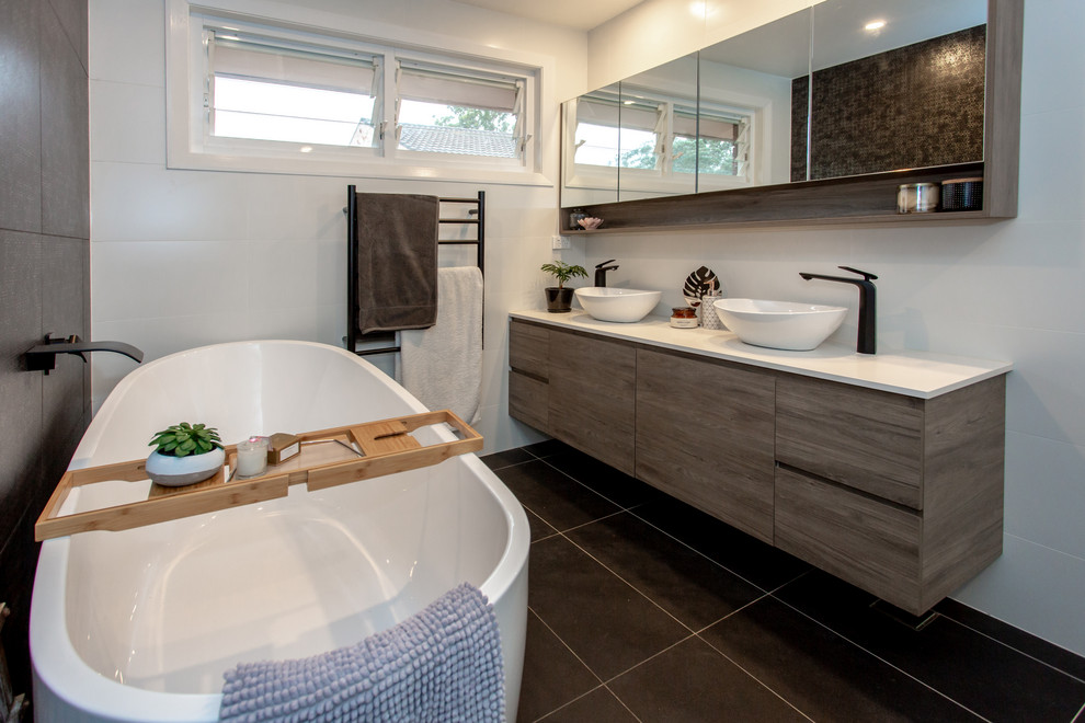 Mid-sized contemporary bathroom in Sydney with flat-panel cabinets, medium wood cabinets, a freestanding tub, white tile, ceramic tile, white walls, porcelain floors, a vessel sink, engineered quartz benchtops, grey floor and white benchtops.