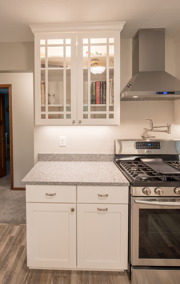 Inspiration for a large transitional u-shaped light wood floor and brown floor enclosed kitchen remodel in Minneapolis with a farmhouse sink, shaker cabinets, white cabinets, granite countertops, stainless steel appliances, a peninsula and gray countertops