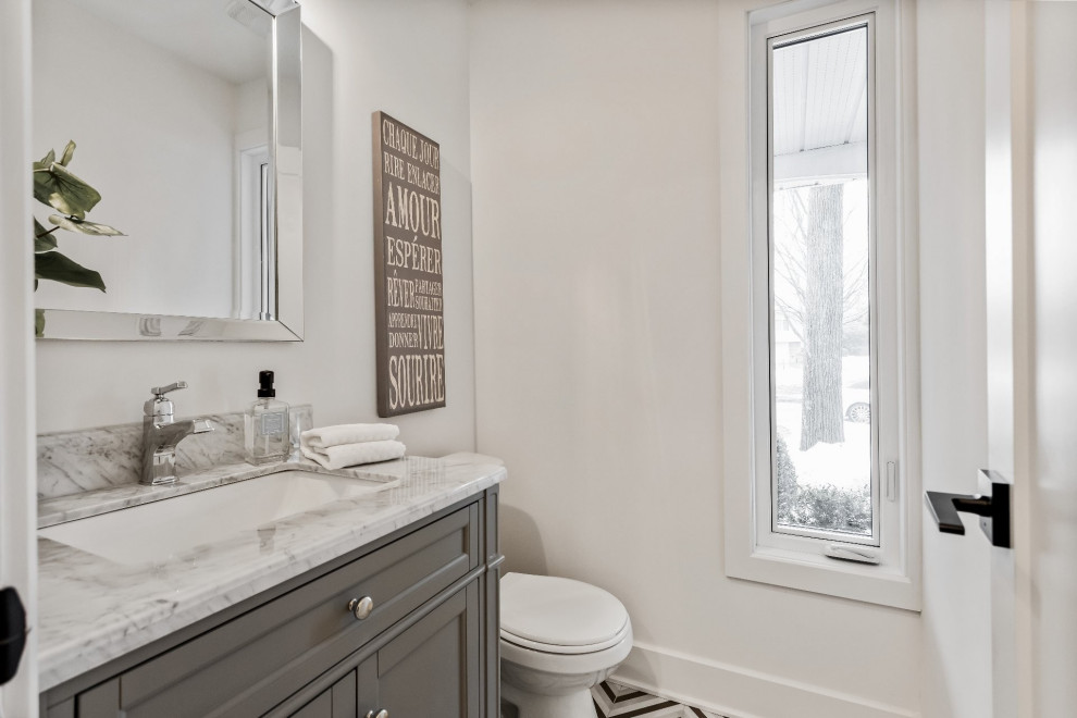 Small country powder room in Montreal with shaker cabinets, grey cabinets, a two-piece toilet, white walls, mosaic tile floors, an undermount sink, marble benchtops, multi-coloured floor, multi-coloured benchtops and a floating vanity.