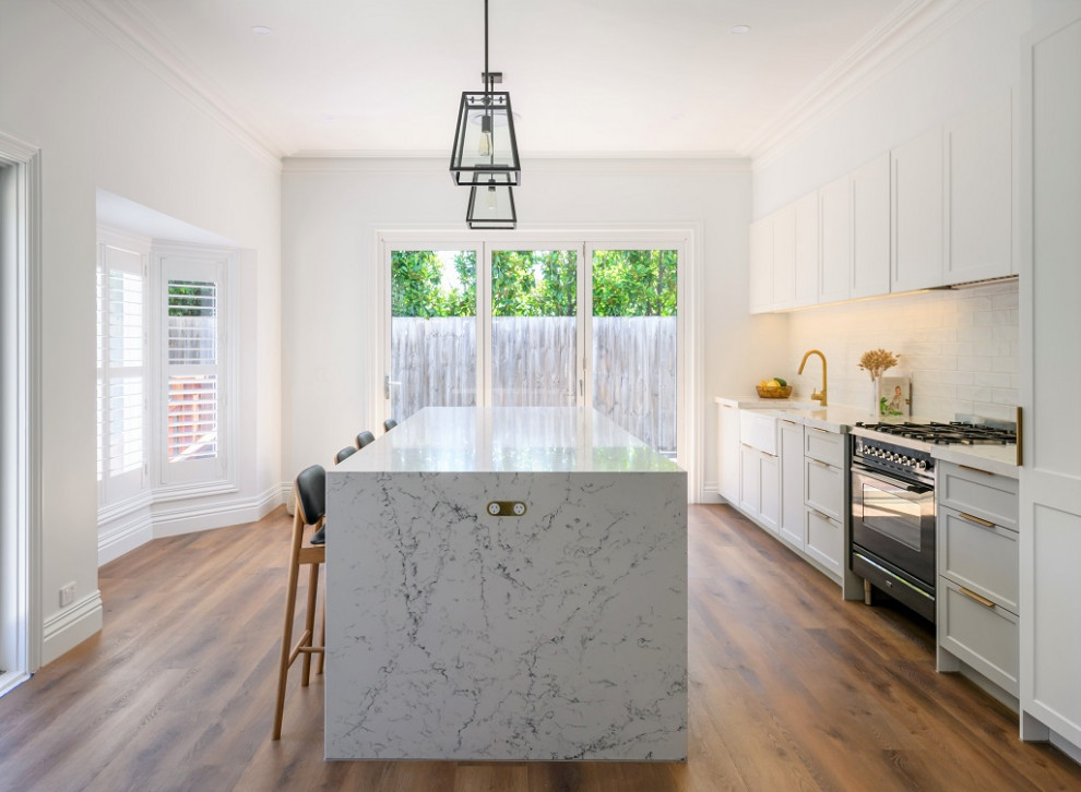 Mid-sized traditional eat-in kitchen in Melbourne with a farmhouse sink, shaker cabinets, grey cabinets, quartz benchtops, ceramic splashback, with island and white splashback.