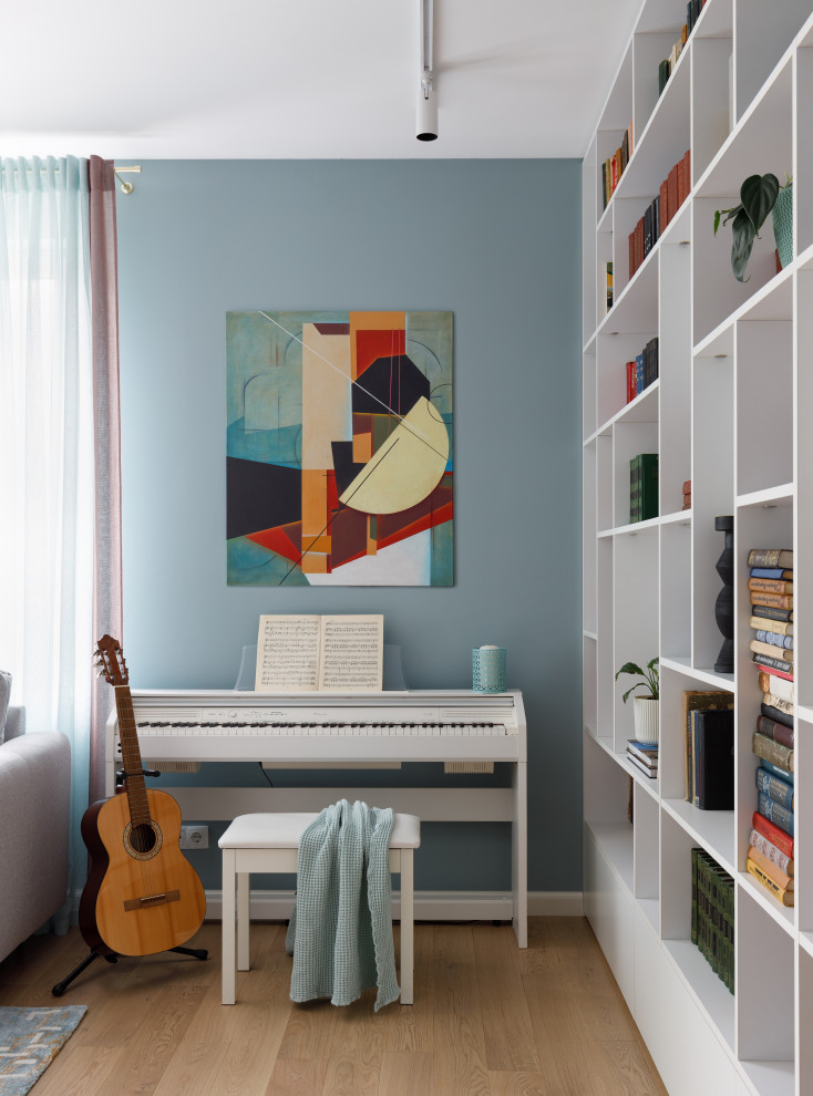 Idee per uno studio contemporaneo di medie dimensioni con libreria, pareti blu e parquet chiaro