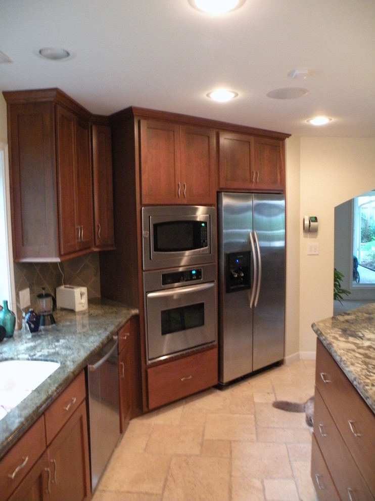 Inspiration for a mid-sized transitional u-shaped limestone floor eat-in kitchen remodel in Houston with an undermount sink, shaker cabinets, medium tone wood cabinets, granite countertops, beige backsplash, ceramic backsplash, stainless steel appliances and an island