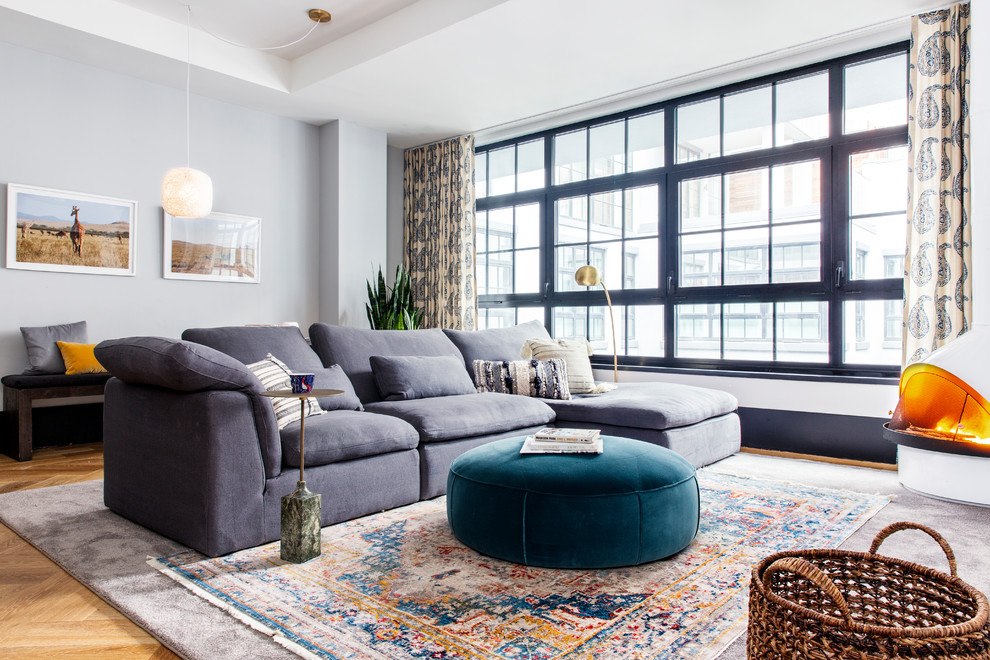 Inspiration for an eclectic open concept medium tone wood floor family room remodel in New York with gray walls and a wood stove