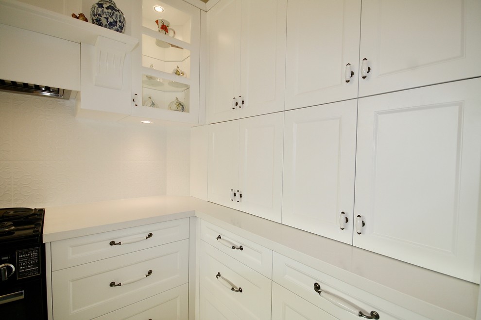 Mid-sized transitional u-shaped eat-in kitchen in Sydney with a farmhouse sink, shaker cabinets, white cabinets, quartz benchtops, white splashback, porcelain splashback, stainless steel appliances, porcelain floors, with island and beige floor.