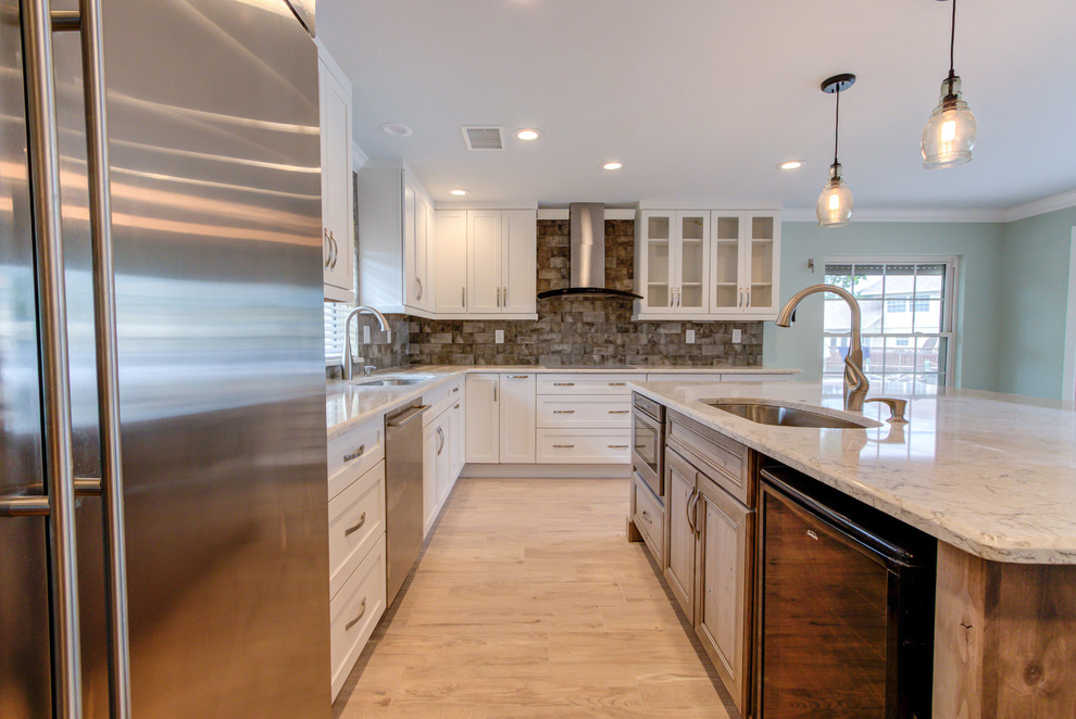 Large transitional u-shaped porcelain tile and brown floor enclosed kitchen photo with an undermount sink, shaker cabinets, white cabinets, quartz countertops, brown backsplash, stainless steel appliances, an island and beige countertops