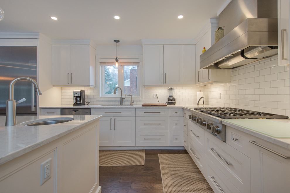 Inspiration for a mid-sized transitional l-shaped eat-in kitchen in Toronto with a double-bowl sink, white cabinets, quartzite benchtops, white splashback, porcelain splashback, stainless steel appliances, medium hardwood floors, with island, recessed-panel cabinets and brown floor.