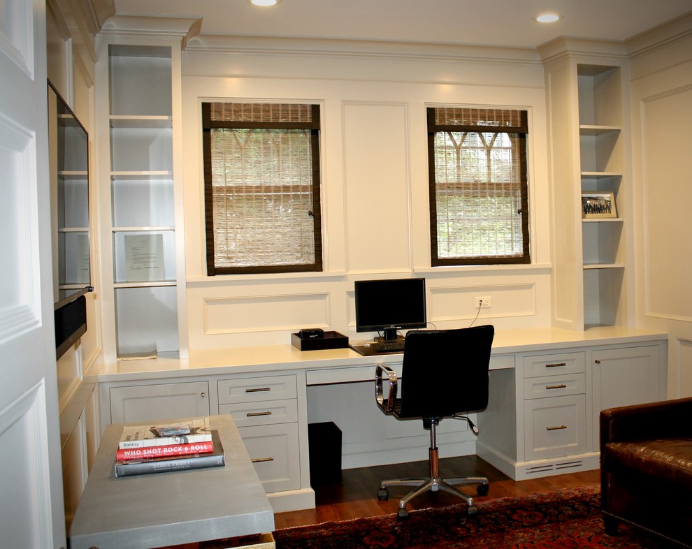 This is an example of a large transitional study room in New York with white walls, medium hardwood floors, a built-in desk and brown floor.