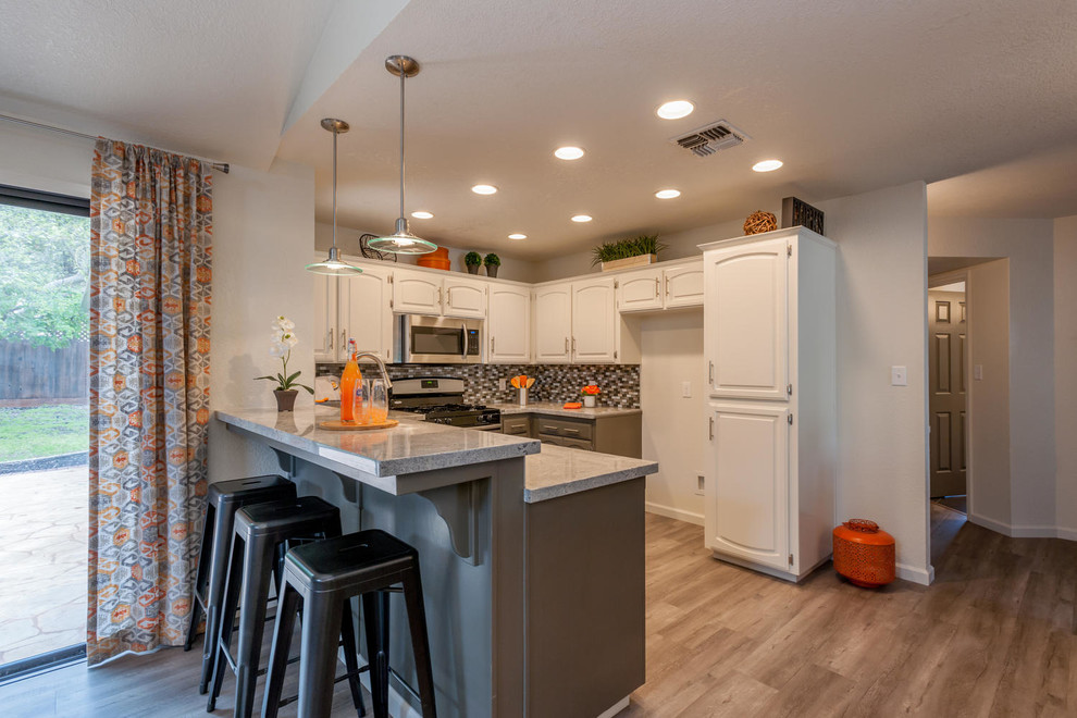 Inspiration for a mid-sized transitional u-shaped medium tone wood floor and brown floor open concept kitchen remodel with an undermount sink, raised-panel cabinets, beige cabinets, granite countertops, multicolored backsplash, ceramic backsplash, stainless steel appliances, a peninsula and beige countertops