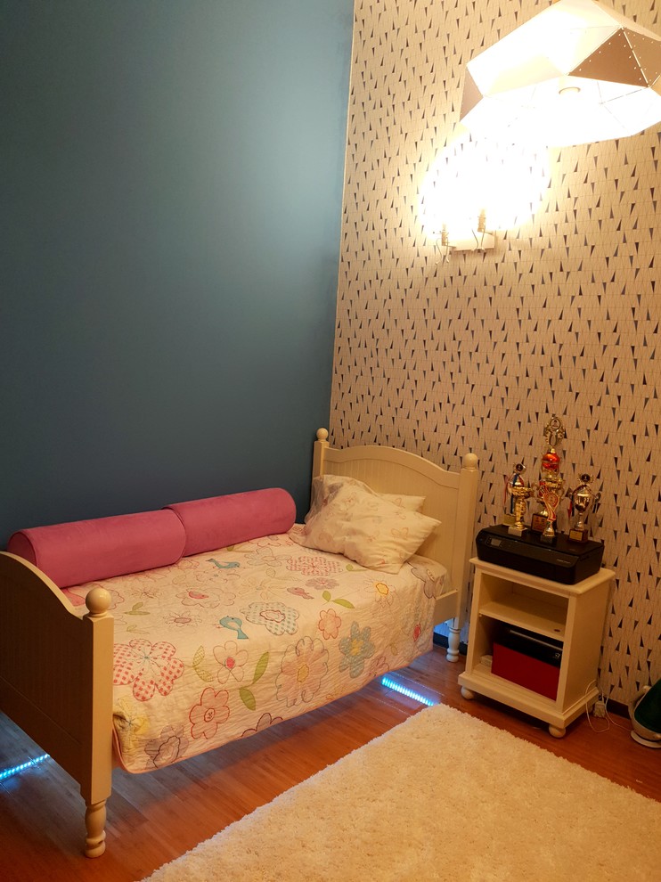 This is an example of a mid-sized modern kids' room for girls in Other with blue walls and laminate floors.