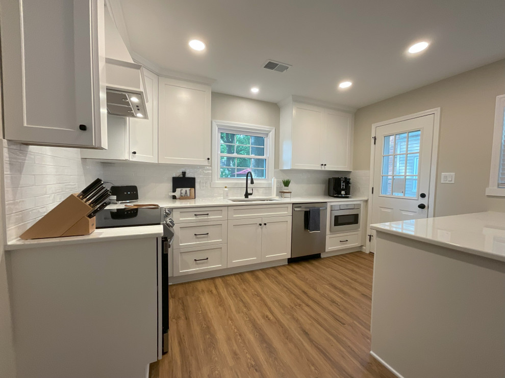 Small transitional l-shaped medium tone wood floor and brown floor eat-in kitchen photo in Detroit with an undermount sink, shaker cabinets, white cabinets, quartz countertops, white backsplash, ceramic backsplash, stainless steel appliances, an island and white countertops