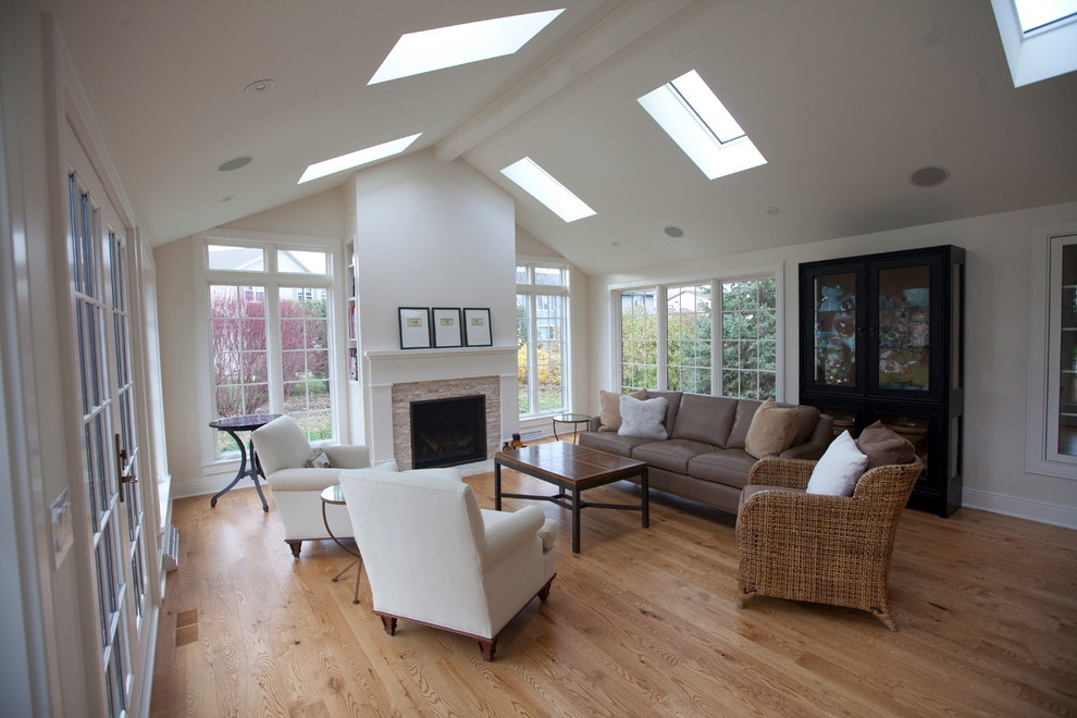 Inspiration for a large sunroom in Other with light hardwood floors, a standard fireplace, a stone fireplace surround and a skylight.