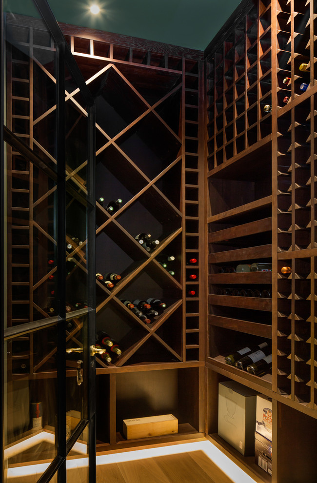Inspiration for a small contemporary wine cellar in London with medium hardwood floors and diamond bins.