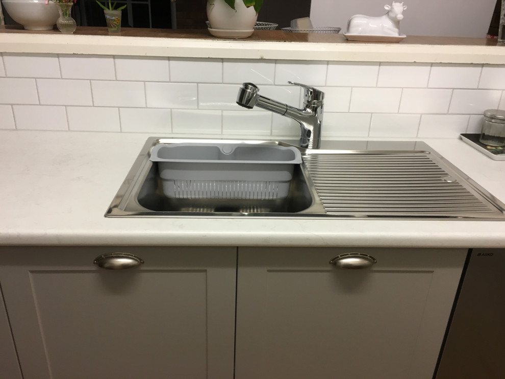 Inspiration for a small modern u-shaped kitchen pantry in Sydney with a drop-in sink, white cabinets, laminate benchtops, white splashback, ceramic splashback, stainless steel appliances, medium hardwood floors, no island, brown floor and white benchtop.