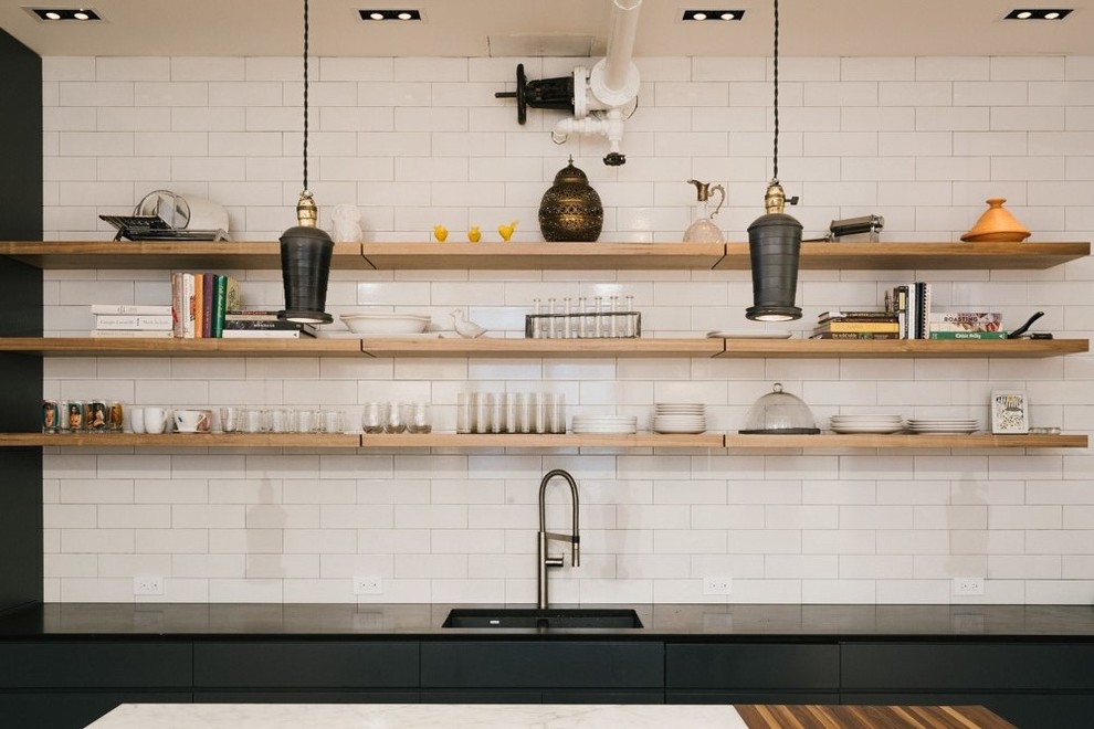 Mid-sized industrial u-shaped eat-in kitchen in New York with an undermount sink, white splashback, flat-panel cabinets, black cabinets, marble benchtops, subway tile splashback, stainless steel appliances, light hardwood floors and with island.