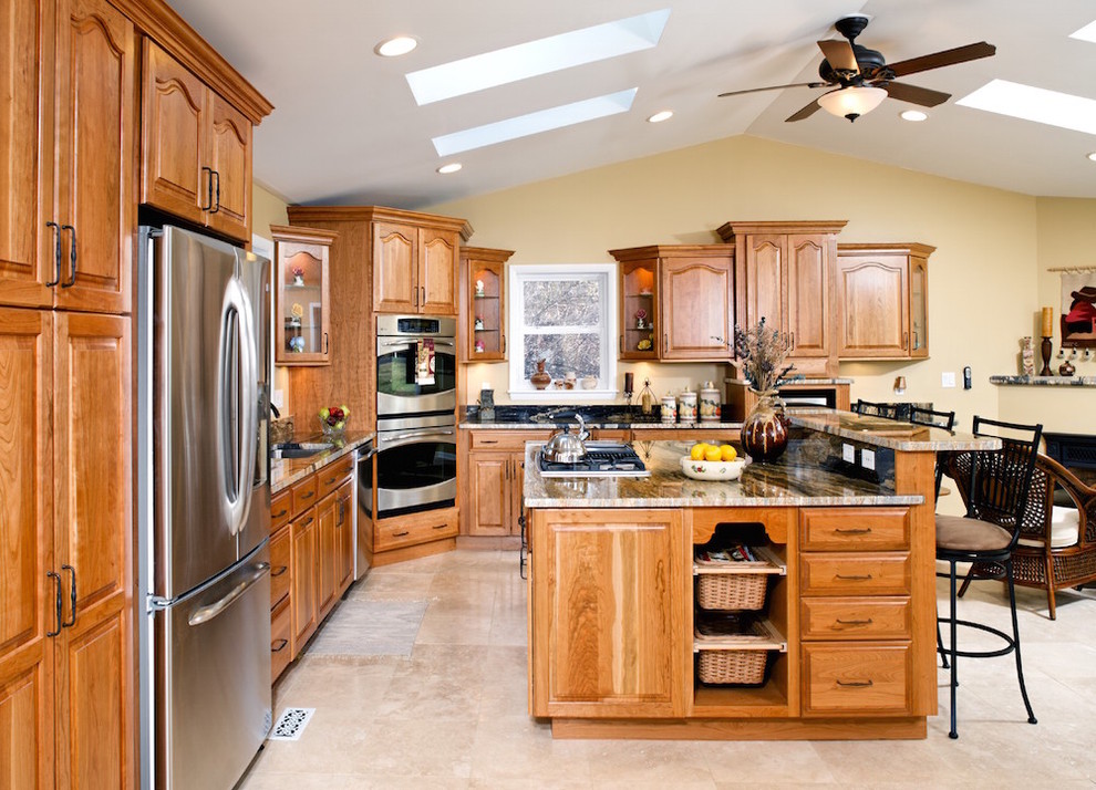 Large traditional l-shaped eat-in kitchen in Baltimore with an undermount sink, recessed-panel cabinets, medium wood cabinets, granite benchtops, stainless steel appliances, medium hardwood floors and with island.