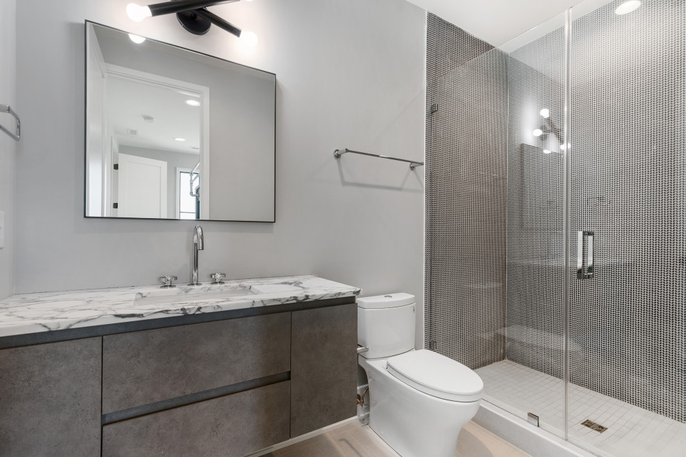 Modernes Badezimmer mit braunen Fliesen, hellem Holzboden, Falttür-Duschabtrennung und Einzelwaschbecken in Charleston