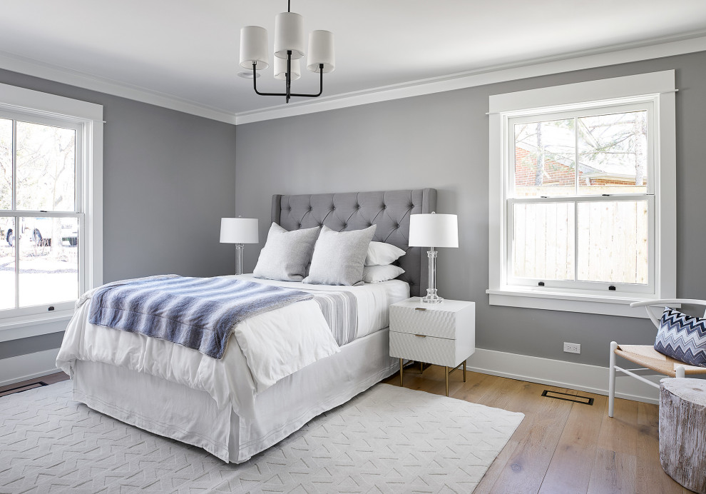 Cette photo montre une chambre d'amis tendance de taille moyenne avec un mur gris, parquet clair et un sol beige.