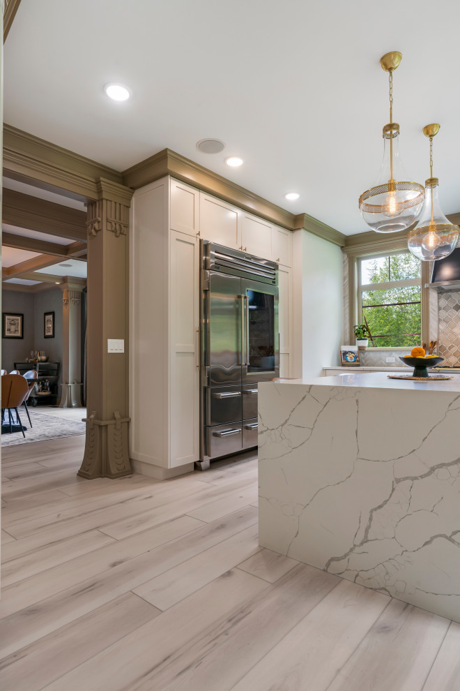 Example of a large classic u-shaped vinyl floor, beige floor and coffered ceiling enclosed kitchen design in Seattle with a drop-in sink, beaded inset cabinets, white cabinets, marble countertops, beige backsplash, ceramic backsplash, stainless steel appliances, an island and white countertops