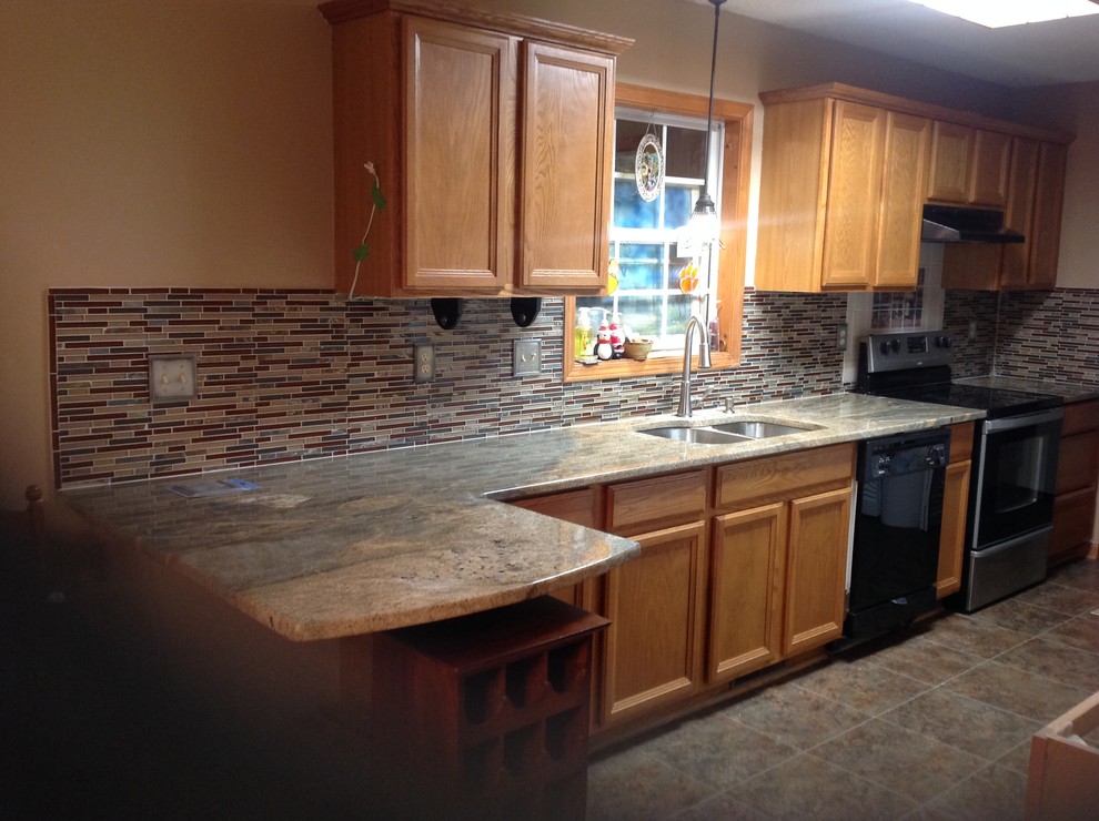 L-shaped eat-in kitchen photo with an undermount sink, flat-panel cabinets, brown backsplash, glass tile backsplash, stainless steel appliances and a peninsula