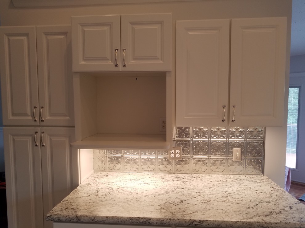 Kitchen - mid-sized transitional u-shaped porcelain tile and gray floor kitchen idea in Cincinnati with a drop-in sink, raised-panel cabinets, white cabinets, laminate countertops, metallic backsplash, metal backsplash, white appliances, no island and gray countertops