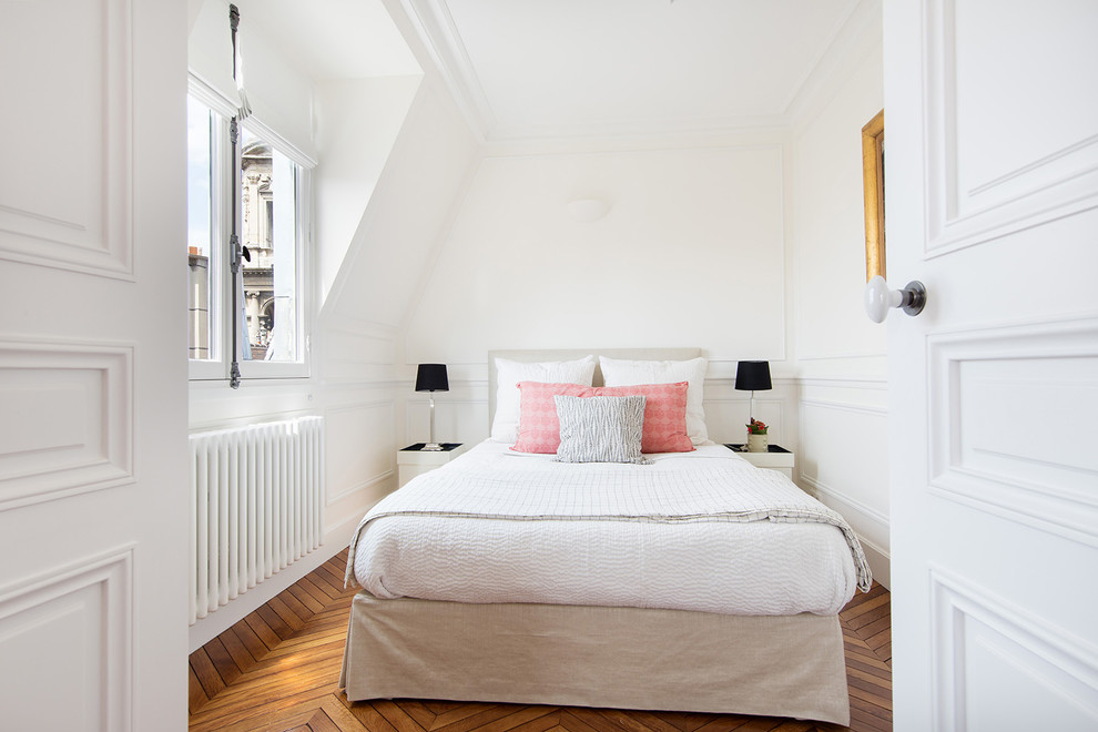 This is an example of a transitional bedroom in Paris with white walls and light hardwood floors.