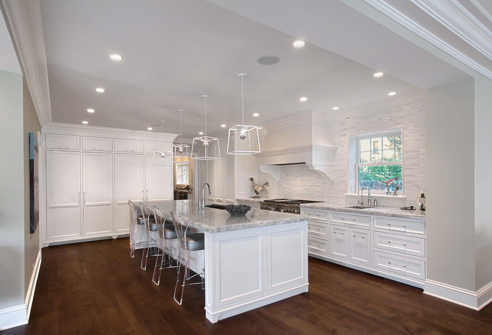 Huge transitional u-shaped medium tone wood floor and brown floor kitchen photo in Chicago with white cabinets, quartzite countertops, white backsplash, stone tile backsplash, an island, an undermount sink, recessed-panel cabinets, stainless steel appliances and gray countertops