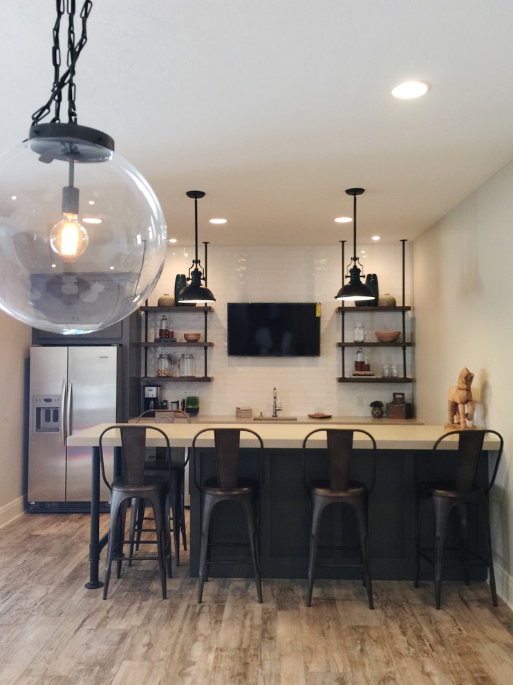 This is an example of an industrial home bar in Indianapolis with quartzite benchtops, white splashback, subway tile splashback and ceramic floors.