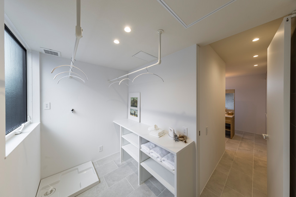Photo of a modern dedicated laundry room in Other with open cabinets, white cabinets, laminate benchtops, white walls, ceramic floors, an integrated washer and dryer, grey floor, white benchtop and wallpaper.