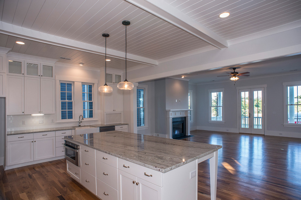 Contemporary l-shaped eat-in kitchen in Charleston with a farmhouse sink, recessed-panel cabinets, white cabinets, granite benchtops, white splashback, ceramic splashback, stainless steel appliances, medium hardwood floors and with island.