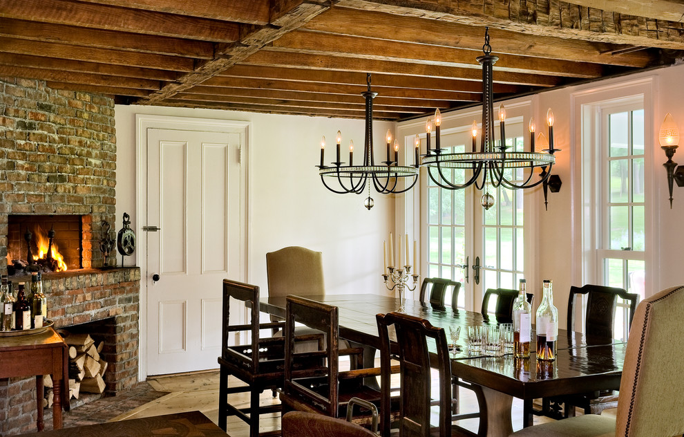 Inspiration for a country dining room in New York with white walls, a corner fireplace and a brick fireplace surround.