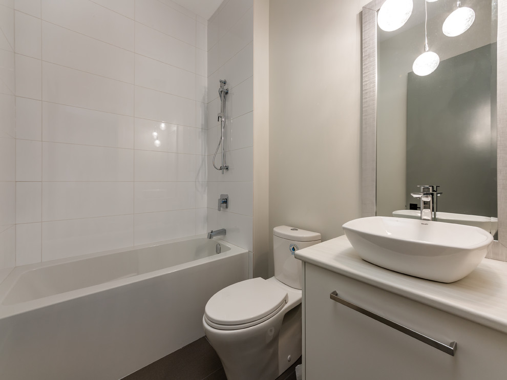 Mid-sized beach style bathroom in Other with grey floor, flat-panel cabinets, white cabinets, an alcove tub, a two-piece toilet, white tile, ceramic tile, beige walls, ceramic floors, laminate benchtops, beige benchtops and a vessel sink.