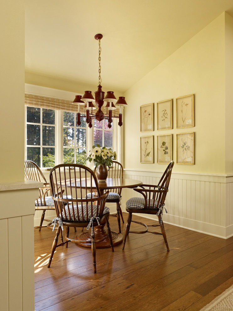 Country dining room in Seattle with yellow walls and dark hardwood floors.