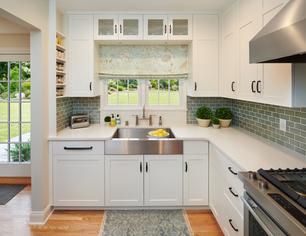 Inspiration for a small transitional u-shaped medium tone wood floor eat-in kitchen remodel with a farmhouse sink, shaker cabinets, white cabinets, quartz countertops, blue backsplash, ceramic backsplash, stainless steel appliances, no island and white countertops