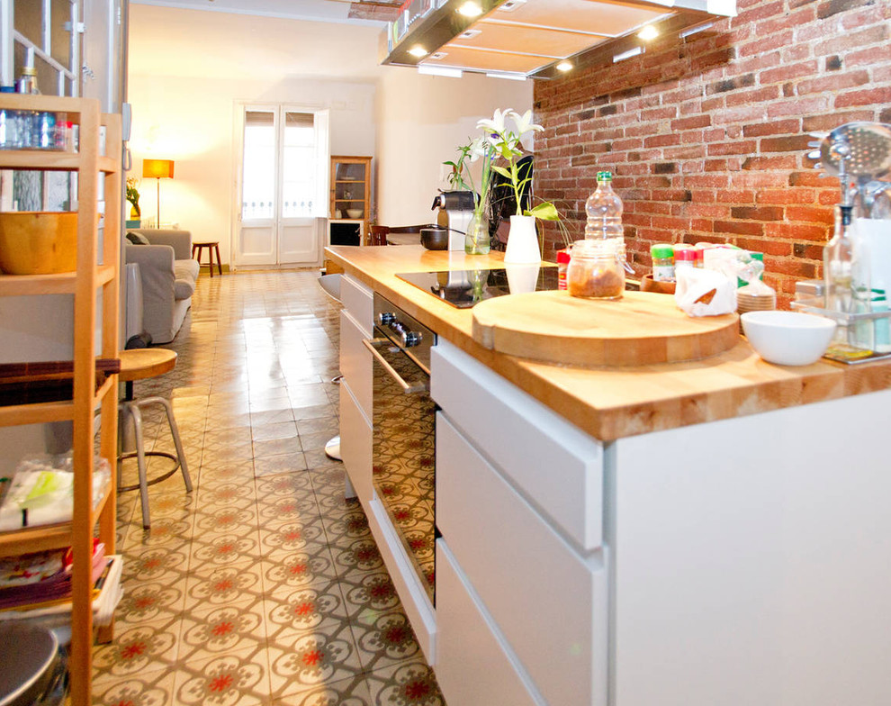 Photo of a small scandinavian single-wall eat-in kitchen in Barcelona with flat-panel cabinets, white cabinets, wood benchtops, cement tiles, with island and multi-coloured floor.