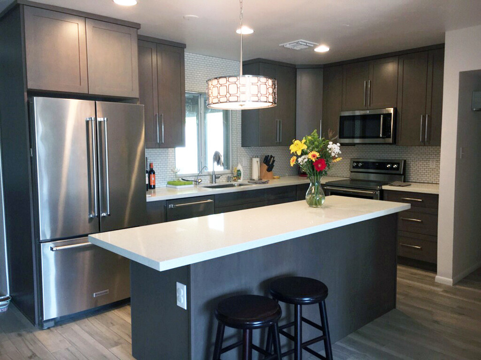 Enclosed kitchen - mid-sized transitional l-shaped medium tone wood floor enclosed kitchen idea in Phoenix with an undermount sink, shaker cabinets, gray cabinets, quartzite countertops, white backsplash, subway tile backsplash, stainless steel appliances and an island