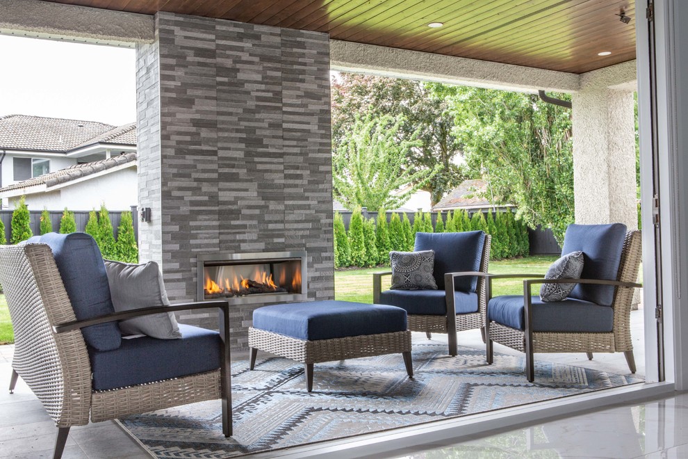 This is an example of a mid-sized transitional backyard patio in Vancouver with with fireplace and a roof extension.