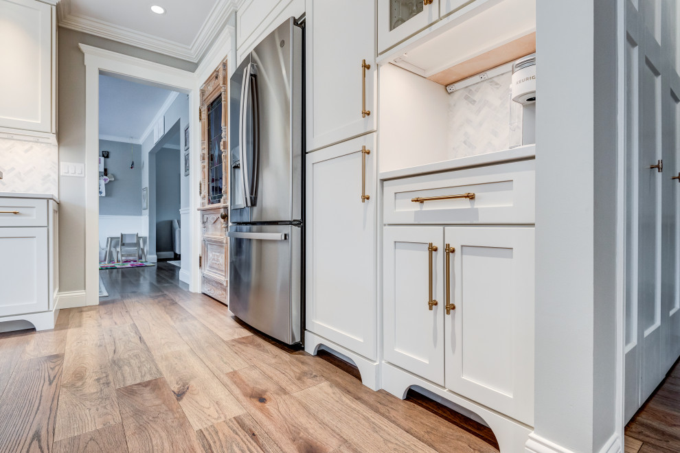 Mid-sized transitional l-shaped light wood floor and brown floor eat-in kitchen photo in Chicago with a farmhouse sink, shaker cabinets, white cabinets, quartzite countertops, white backsplash, glass tile backsplash, colored appliances, an island and white countertops