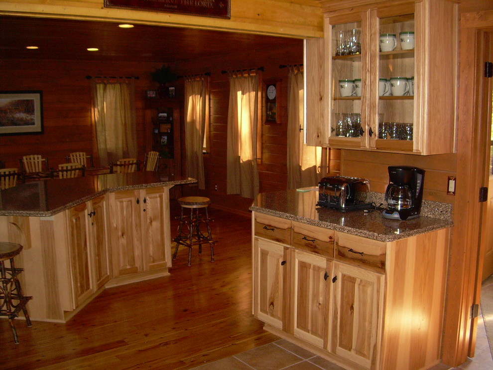 Example of a mid-sized mountain style u-shaped medium tone wood floor and brown floor open concept kitchen design with glass-front cabinets, light wood cabinets, granite countertops, brown backsplash, wood backsplash, stainless steel appliances and an island