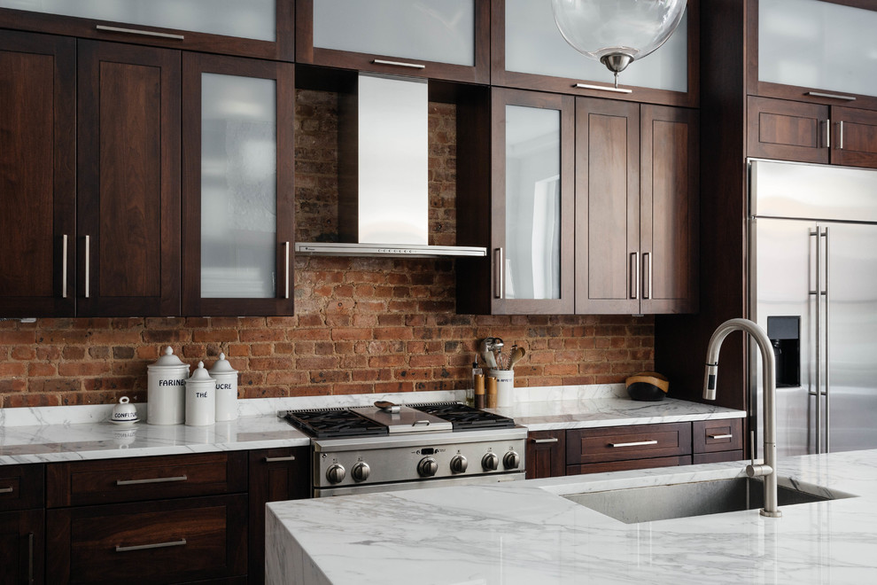 This is an example of a transitional kitchen in New York with an undermount sink, dark wood cabinets, stainless steel appliances and with island.