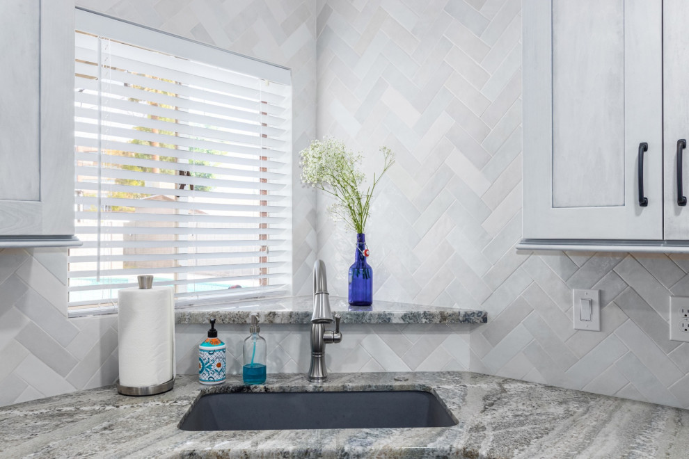 Example of a transitional l-shaped kitchen design in Phoenix with a single-bowl sink, shaker cabinets, white cabinets, granite countertops, white backsplash and stainless steel appliances