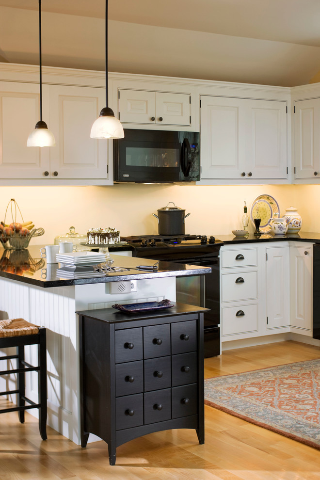 Photo of a country kitchen in Burlington with black appliances and beaded inset cabinets.