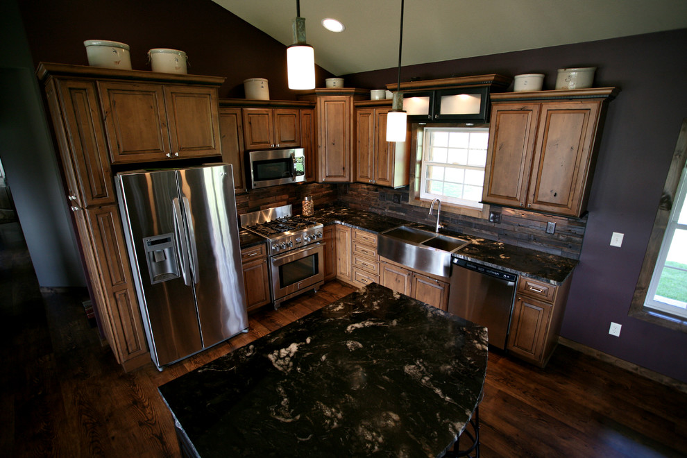 Inspiration for a mid-sized rustic l-shaped dark wood floor and brown floor open concept kitchen remodel in Minneapolis with a farmhouse sink, raised-panel cabinets, medium tone wood cabinets, granite countertops, brown backsplash, wood backsplash, stainless steel appliances and an island