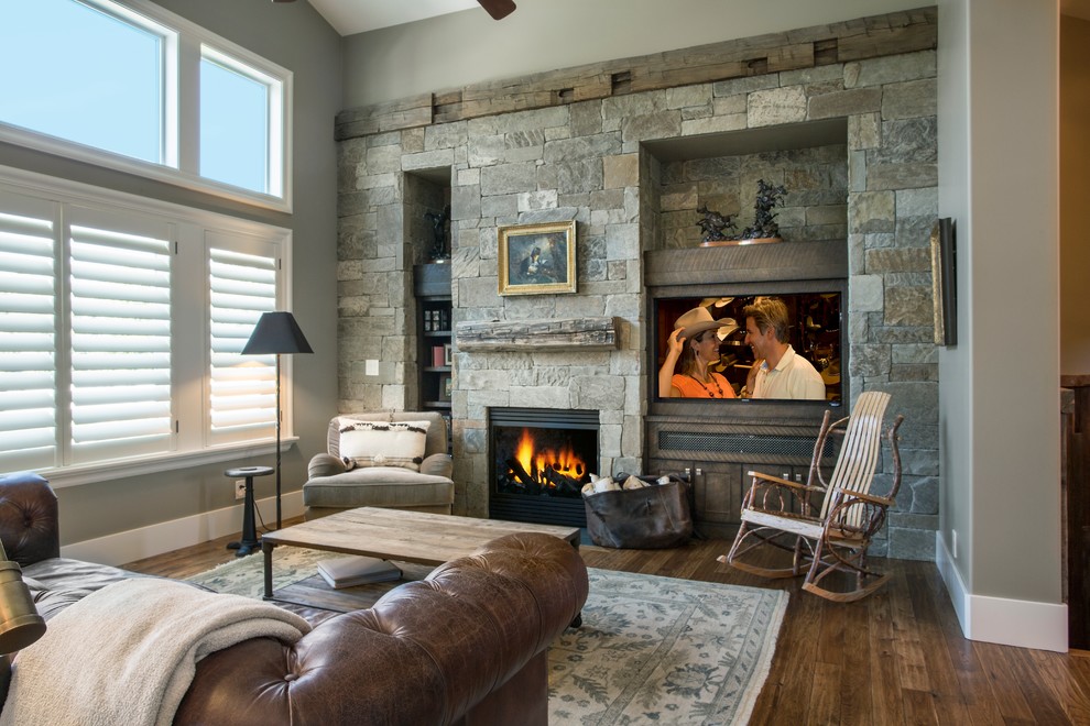 Mid-sized country enclosed family room in Salt Lake City with grey walls, dark hardwood floors, a standard fireplace, a stone fireplace surround, a concealed tv and brown floor.