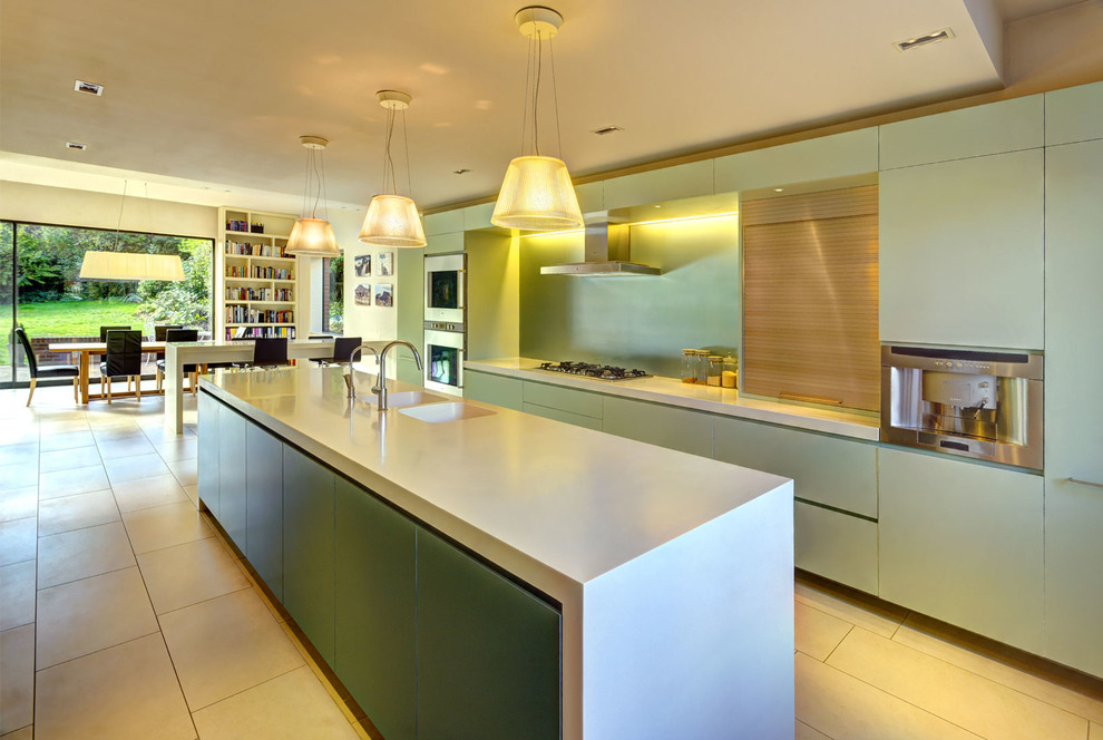 Inspiration for a large modern galley open plan kitchen in London with a drop-in sink, flat-panel cabinets, green cabinets, quartz benchtops, green splashback, glass tile splashback, white appliances, ceramic floors and with island.