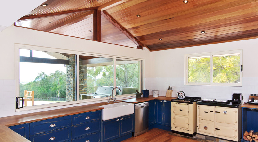 Large country u-shaped eat-in kitchen in Other with a farmhouse sink, beaded inset cabinets, blue cabinets, wood benchtops, white splashback, subway tile splashback, coloured appliances, a peninsula and light hardwood floors.