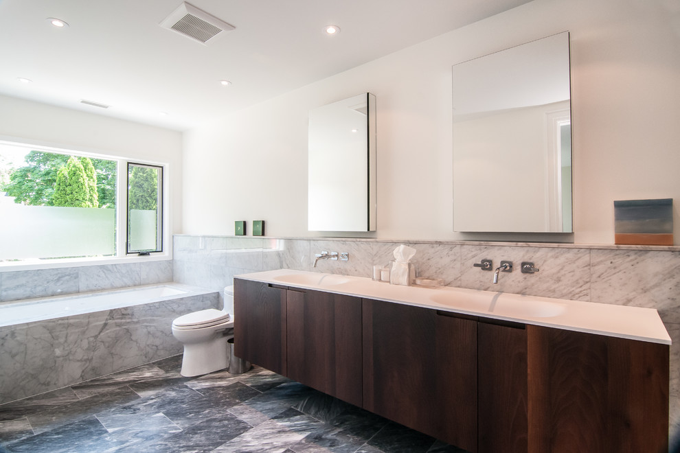 Inspiration for a large eclectic master bathroom in Toronto with flat-panel cabinets, dark wood cabinets, a drop-in tub, a one-piece toilet, gray tile, stone slab, white walls, porcelain floors, a drop-in sink and engineered quartz benchtops.