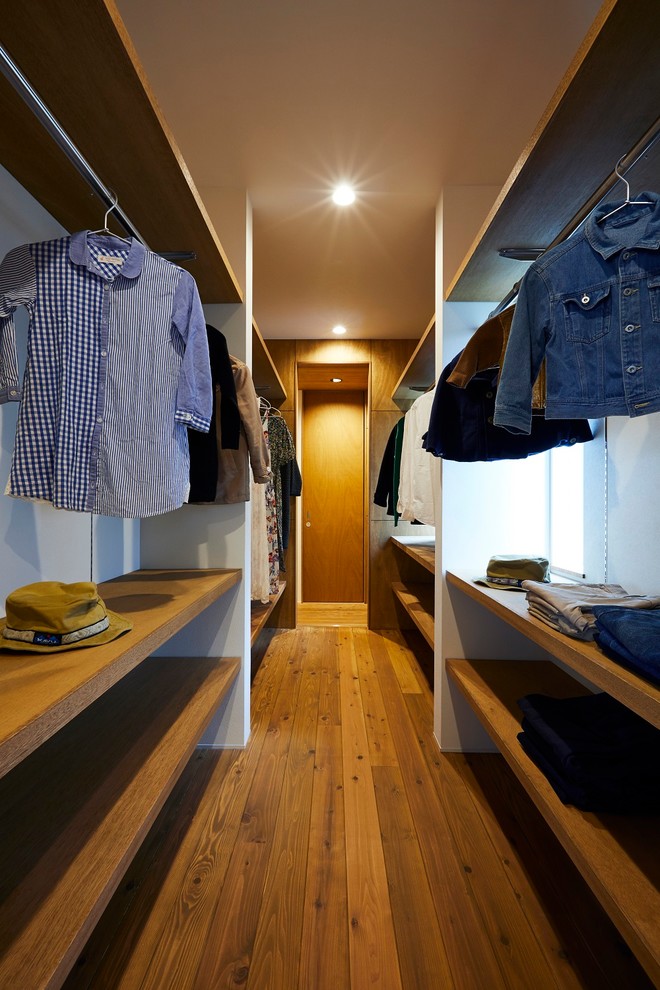 Diseño de vestidor unisex minimalista de tamaño medio con armarios abiertos, puertas de armario marrones, suelo de madera oscura y suelo marrón
